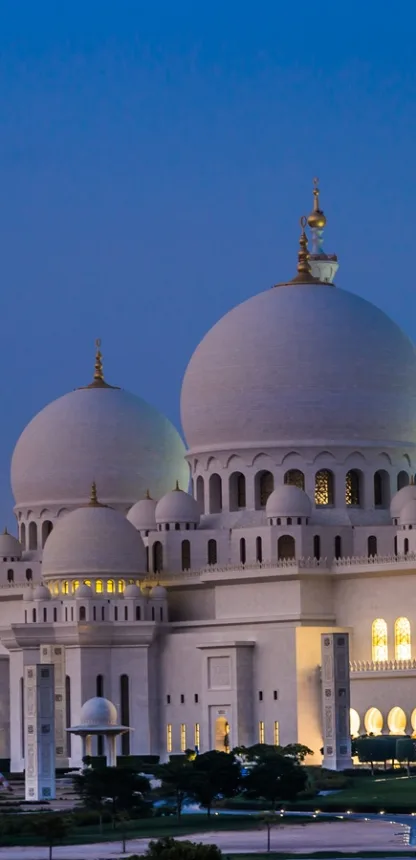 Sheikh Zayed Grand Mosque in Abu Dhabi at dusk, with its white marble domes lit up