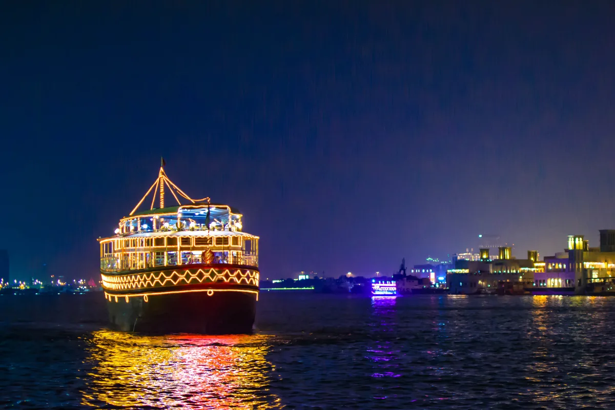 A lit dhow dinner cruise boat on the water at night