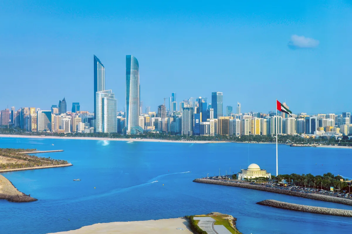 The Abu Dhabi skyline seen across the water, with the UAE flag on the corniche