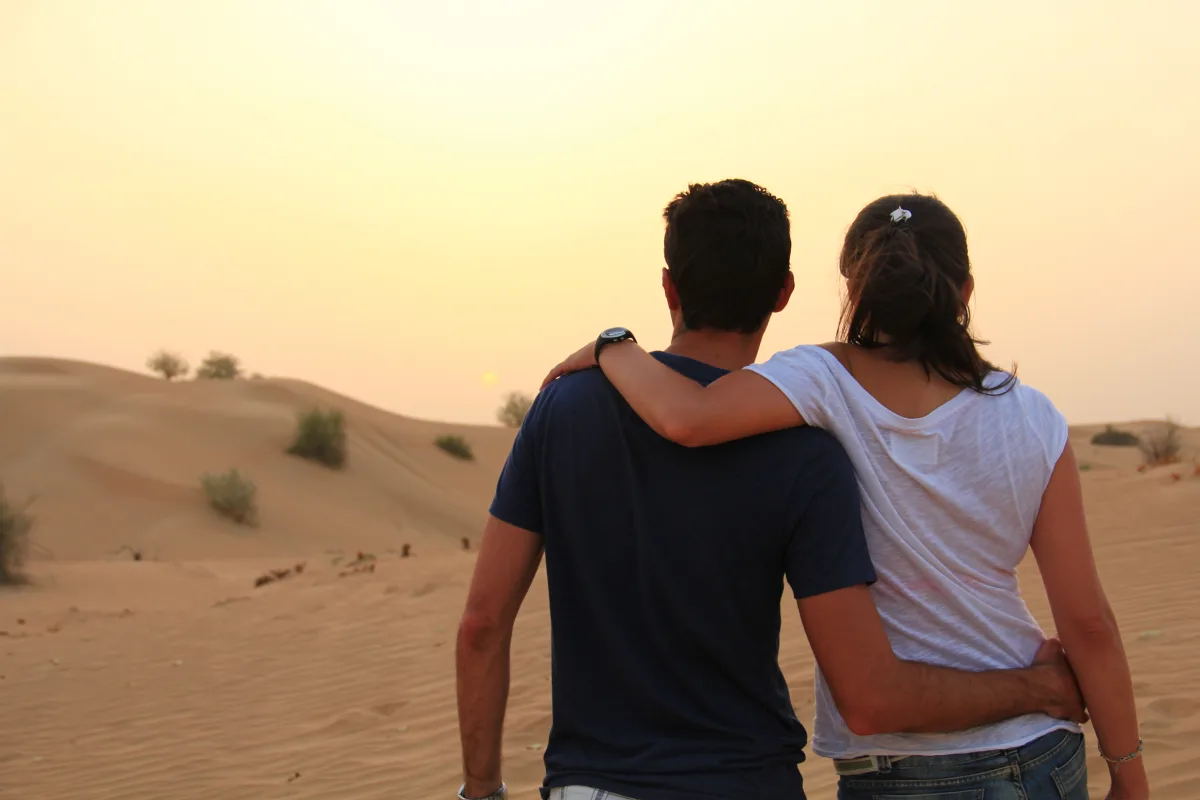 A couple looking out over the desert dunes at sunset