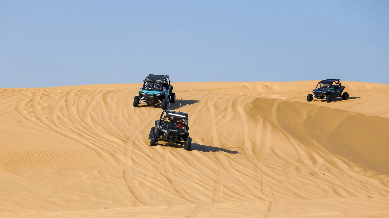 Off-road buggy driving across the vast golden sand dunes in the Abu Dhabi desert