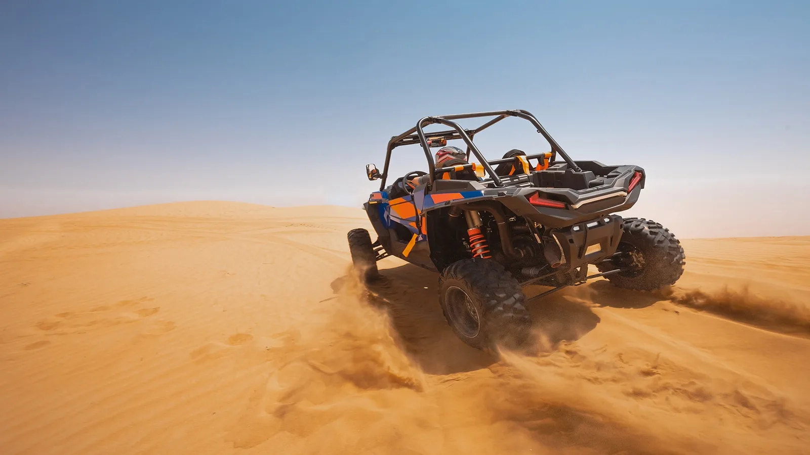 Tourist driving a desert buggy across the golden sand dunes during an Abu Dhabi desert adventure