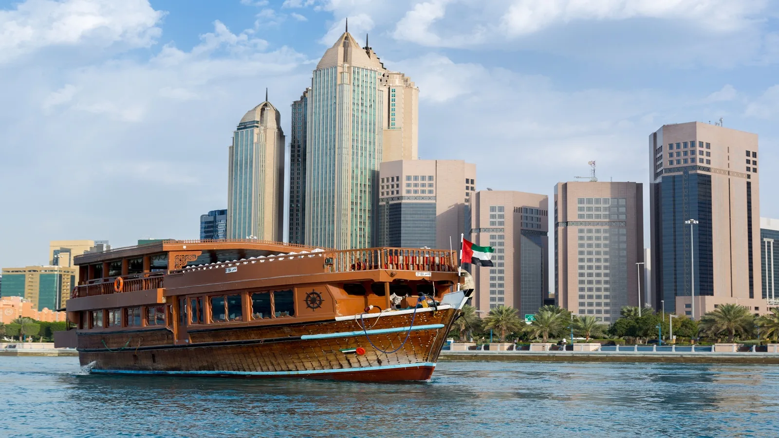 Traditional Arabian dhow cruising along Abu Dhabi Corniche with panoramic views of the Abu Dhabi skyline