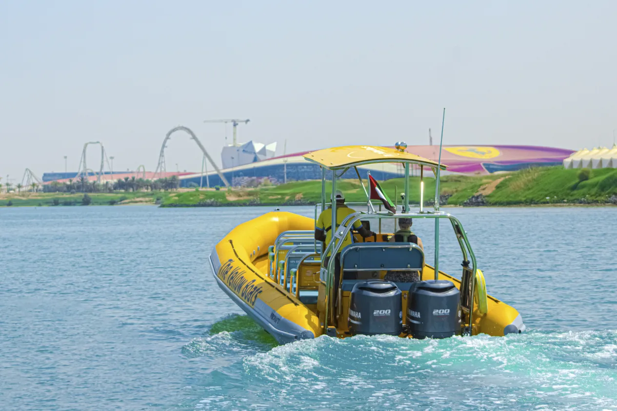 Yellow Boat Tour cruising near Ferrari World Abu Dhabi on Yas Island with the iconic red roof in the background