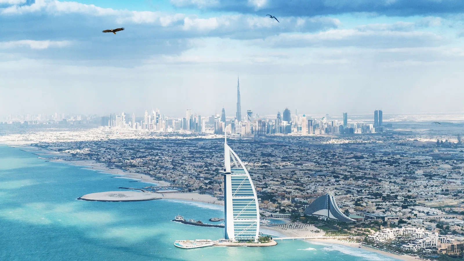 Burj Al Arab standing on its iconic island in the Arabian Gulf with Dubai coastline views