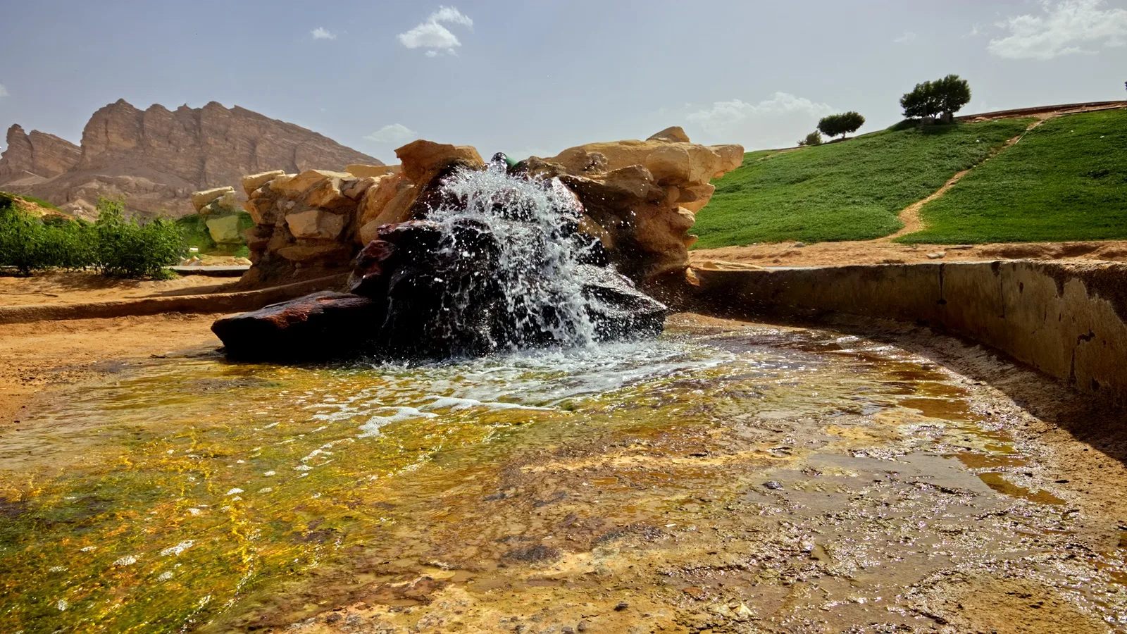 Green Mubazzarah with lush greenery, natural hot springs, and Jebel Hafeet mountain in Al Ain