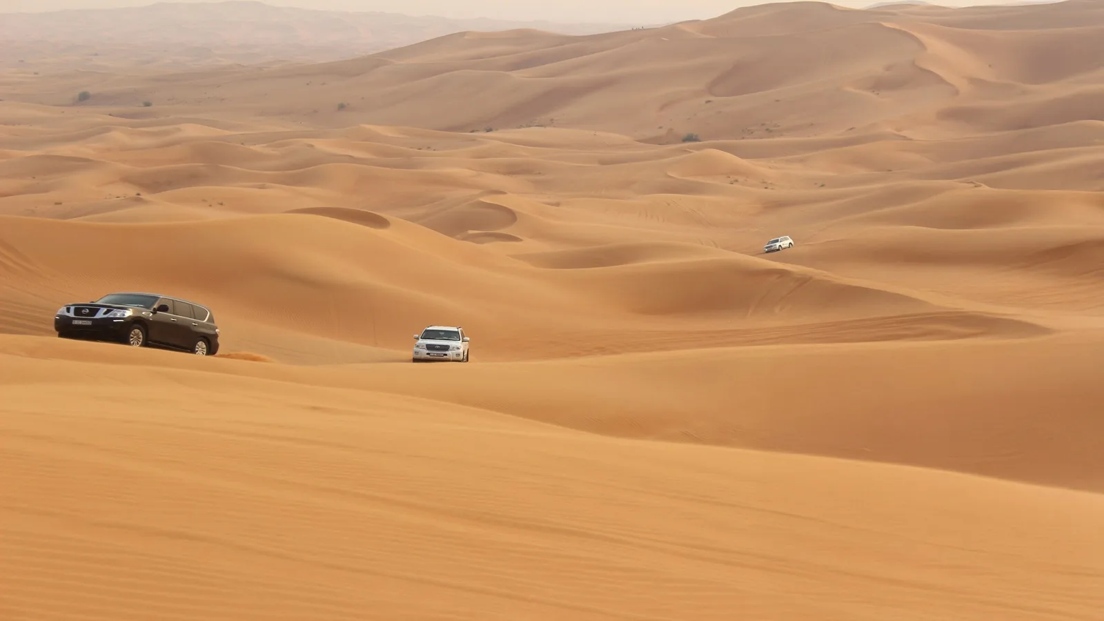 4x4 vehicle dune bashing across the golden sand dunes in the middle of the Arabian Desert