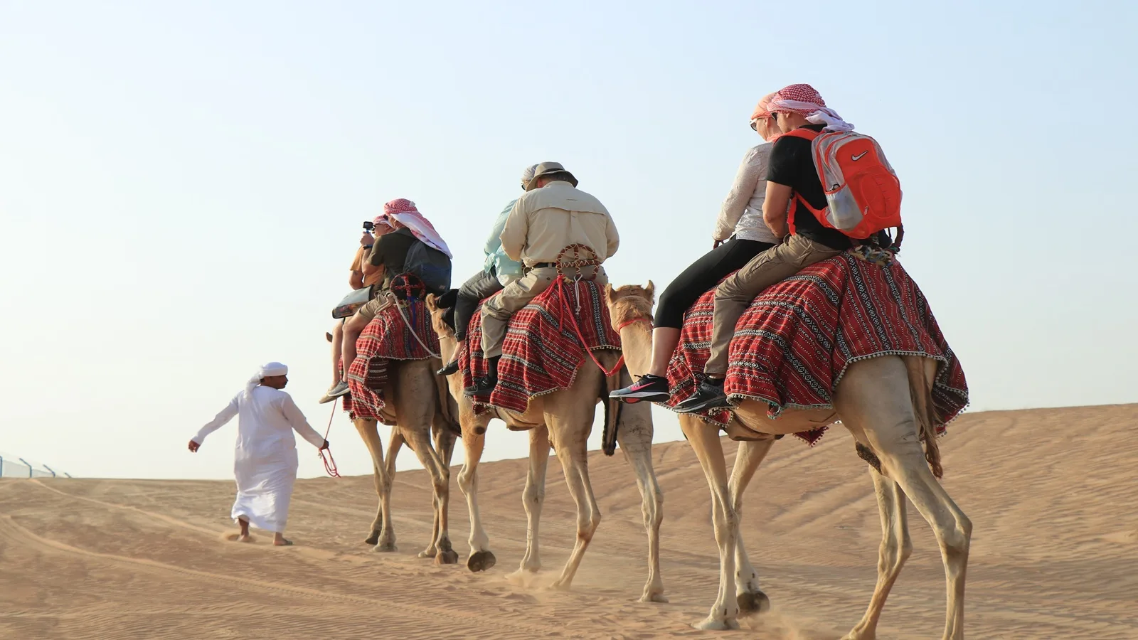 Tourist enjoying a traditional camel ride across the golden dunes during a Morning Desert Safari in Abu Dhabi
