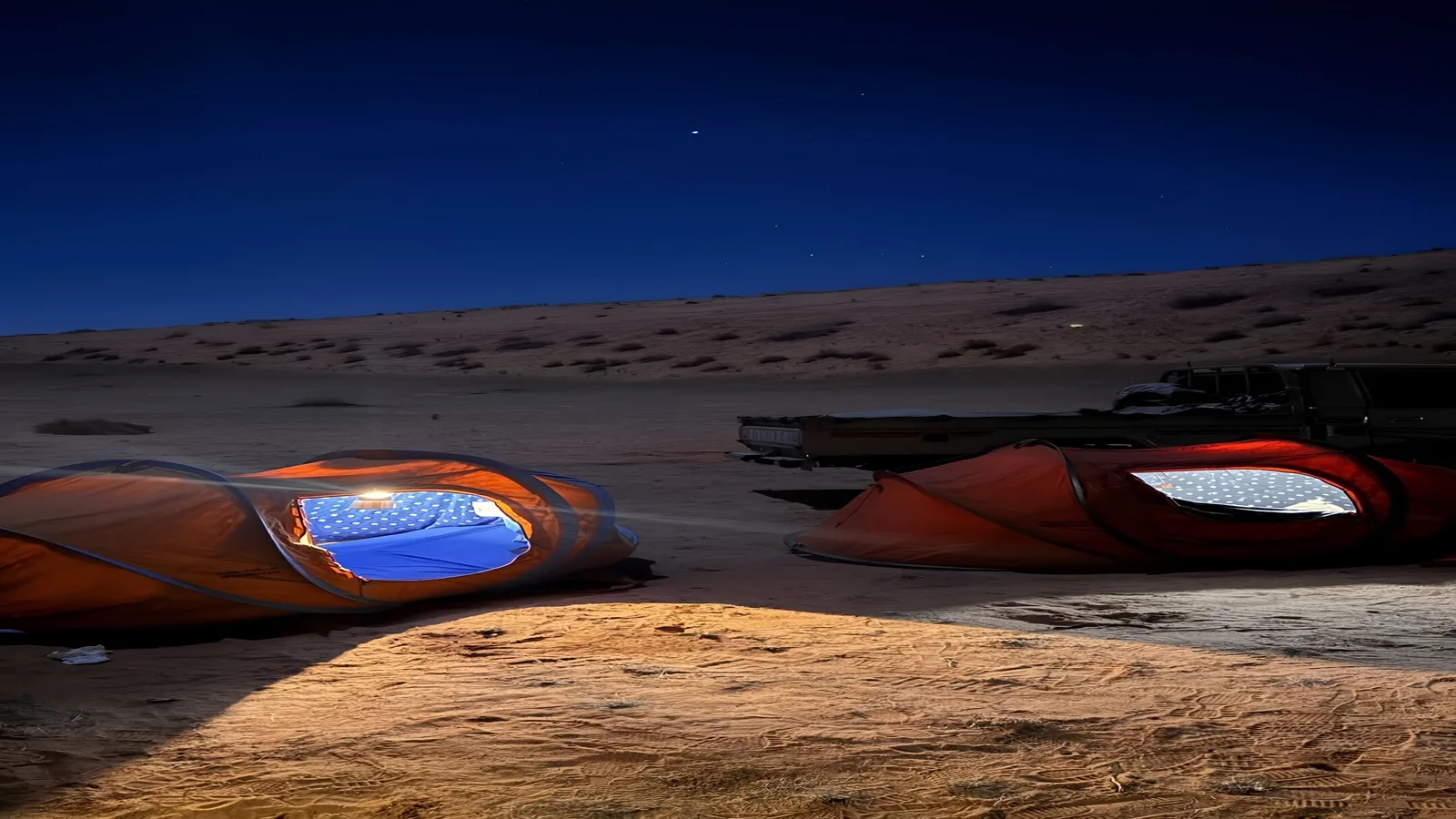 Desert camping tent beside a glowing campfire under the starry sky during an Overnight Desert Safari